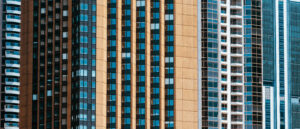 Tight telephoto view of tall city apartment and office towers, repeating vertical patterns of windows and balconies.