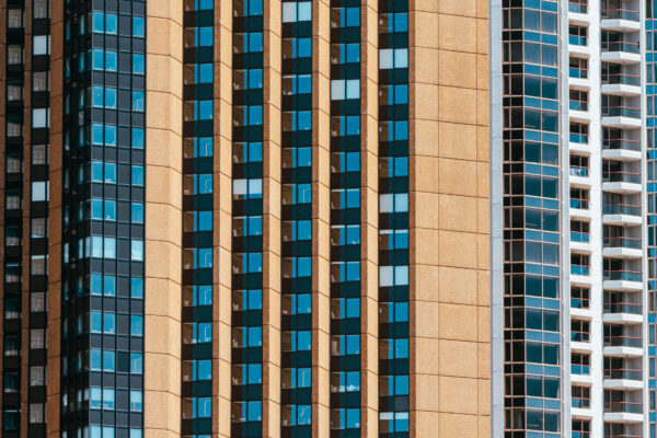 Tight telephoto view of tall city apartment and office towers, repeating vertical patterns of windows and balconies.
