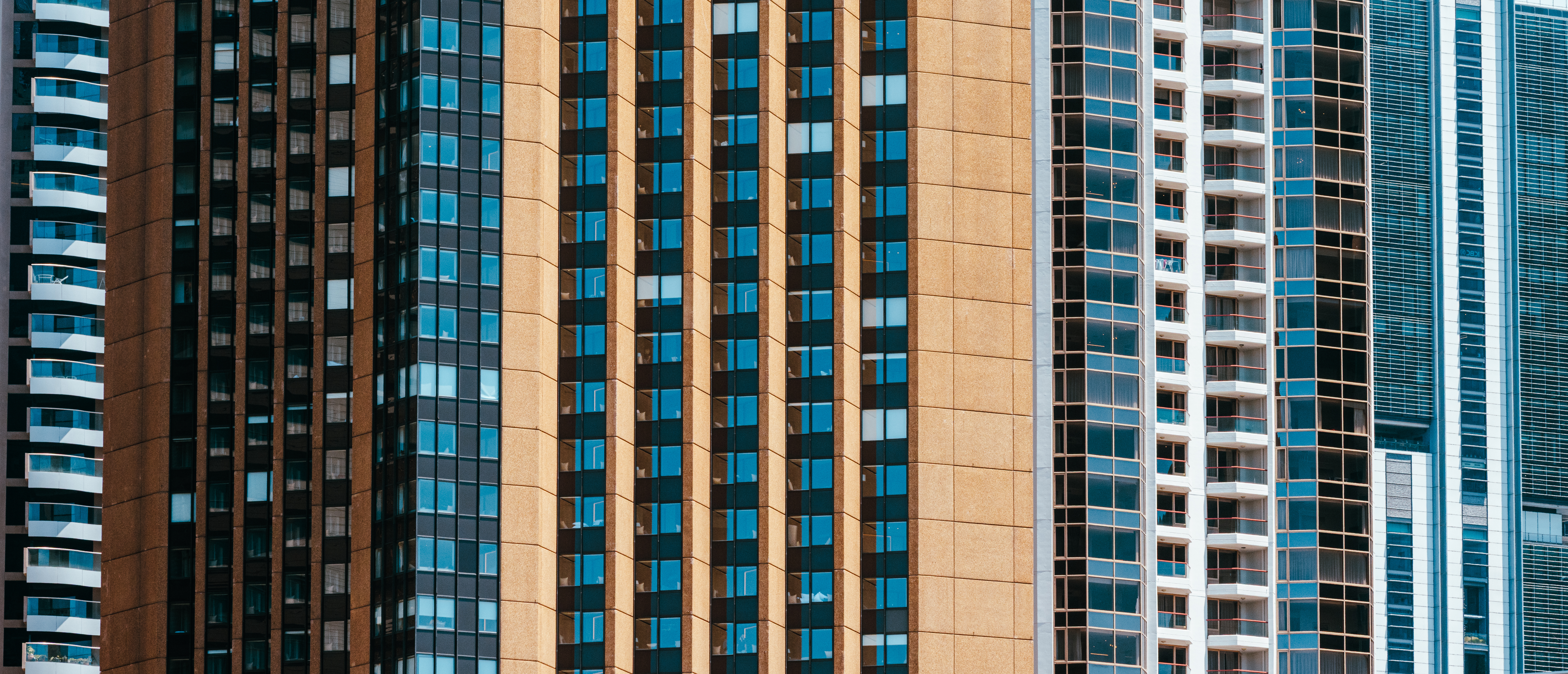 Tight telephoto view of tall city apartment and office towers, repeating vertical patterns of windows and balconies.