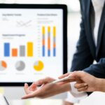 Professional business partners analyzing complex financial dashboard and colorful charts on laptop in a modern office.