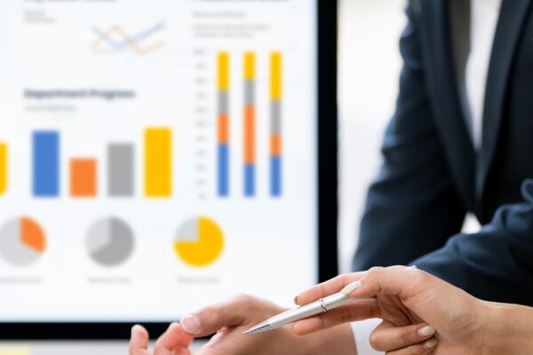 Professional business partners analyzing complex financial dashboard and colorful charts on laptop in a modern office.