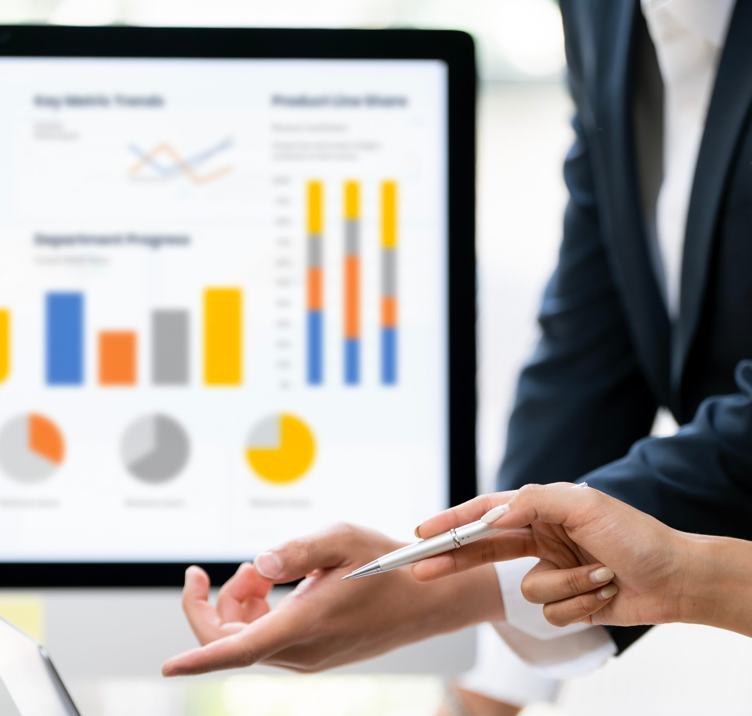 Professional business partners analyzing complex financial dashboard and colorful charts on laptop in a modern office.
